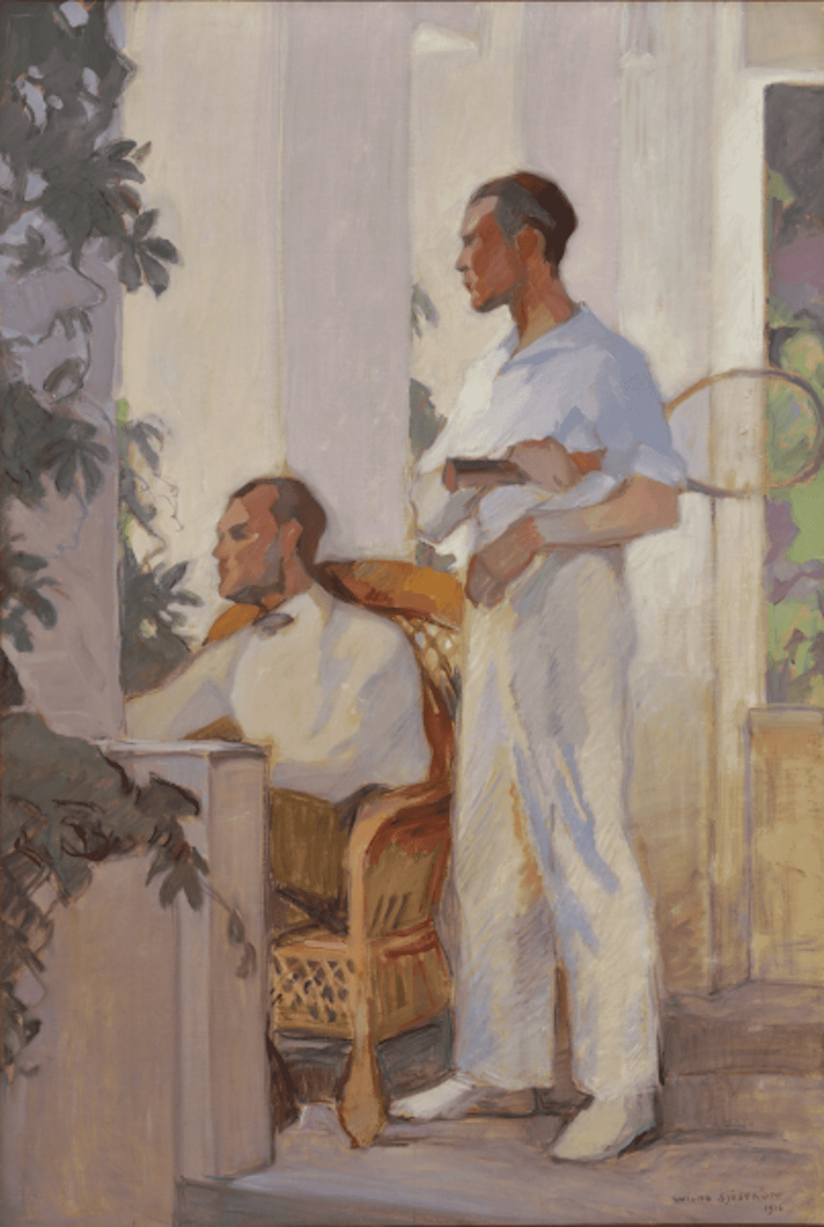 Two slender young men, dressed in light colored clothes on a deck looking out in the garden, one sitting in a garden chair the other standing and holding a tennis racket under his arm.