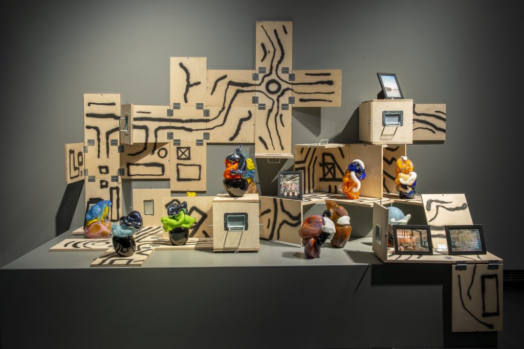 I utställningssalen står På mångfärgade glasskulpturer med sina transportlådor på en skulpturplattform.