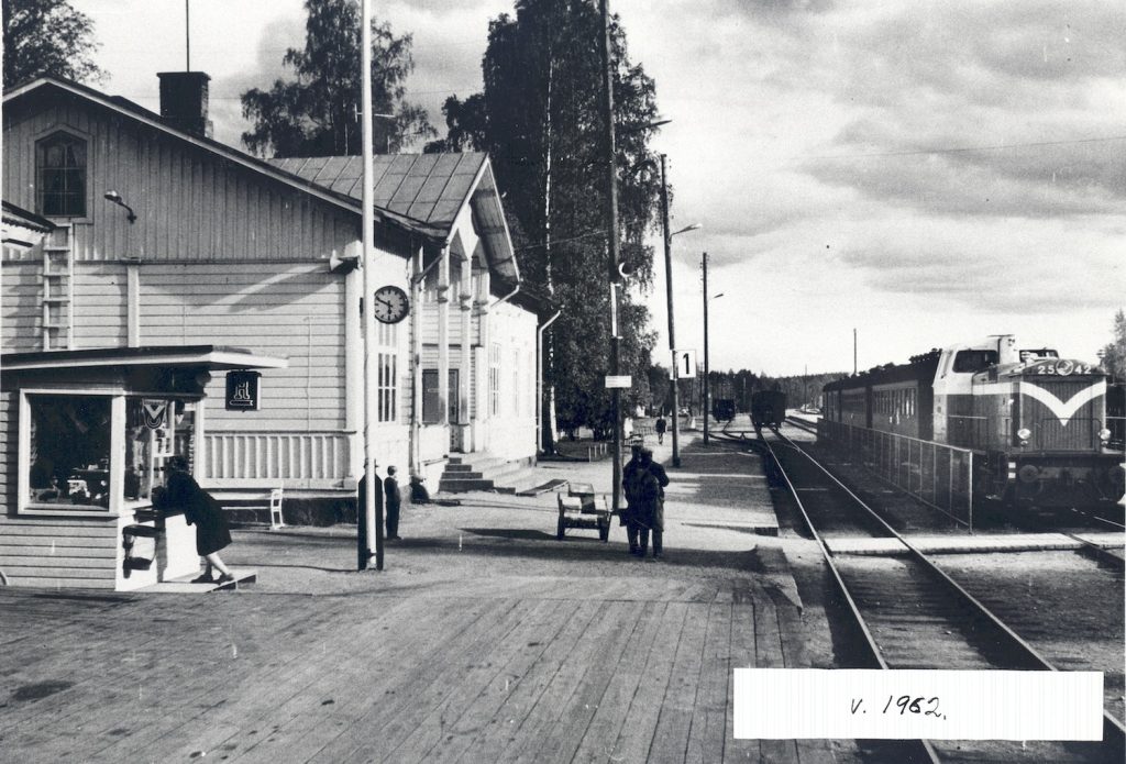 1960-luvun alussa katon puuleikkauskoristeet olivat jo kadonneet. Asemarakennuksen vieressä oli Rautatiekirjakaupan kioski, jossa roikkui 1950-luvulla lanseerattu R-kyltti. Kuva: Vilppula-Seuran kokoelma. Serlachius-museot, kuva-arkisto.