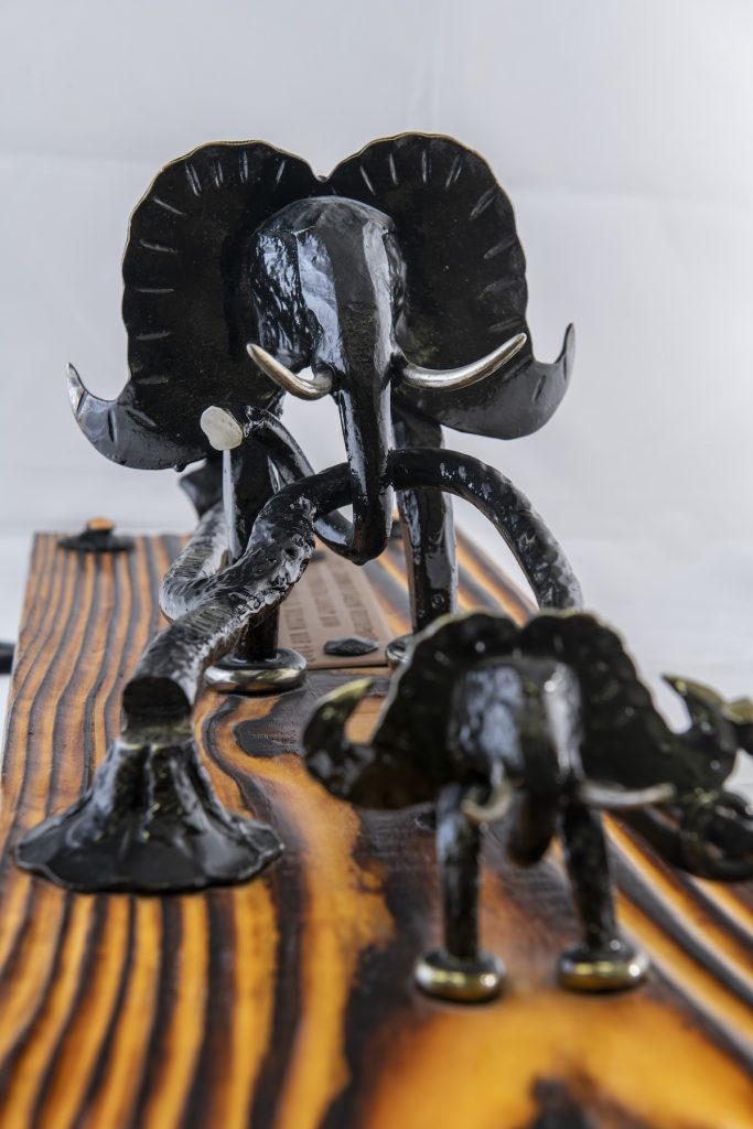 Svarta elefanfigurera gjorda av metal häftade på brun trä.