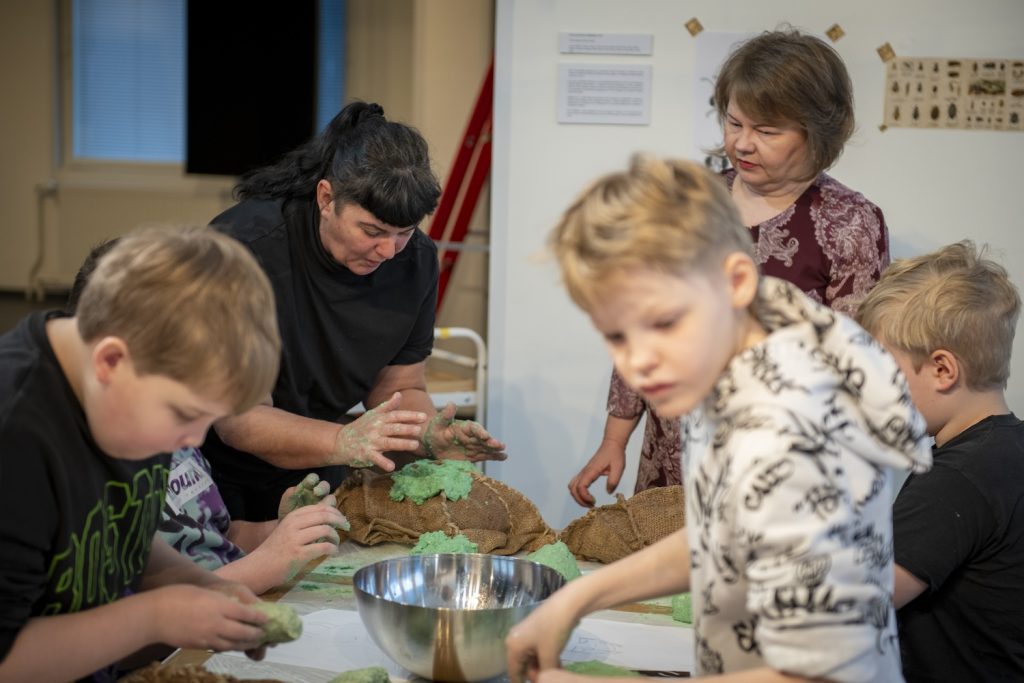 Anita Gratzer ja Maarit Lampinen ohjaavat Vilppulankosken koulun oppilaita maskien teossa. Kuva: Serlachius, Sampo Linkoneva