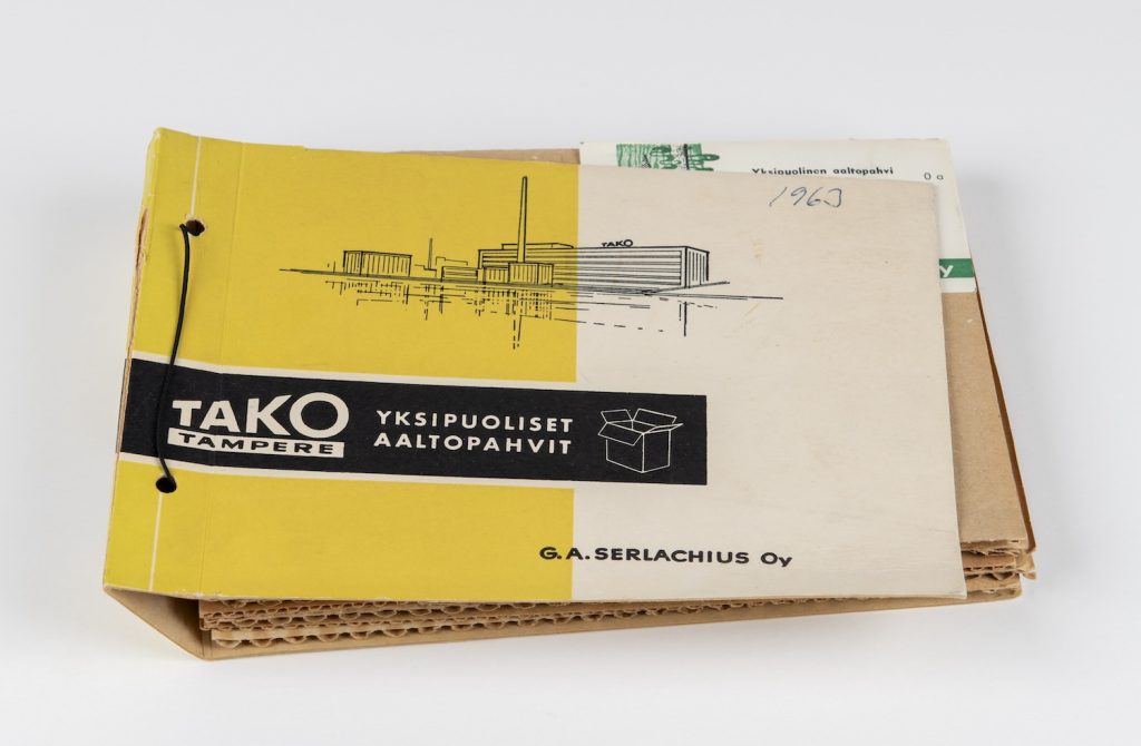 Kansio aaltopahvinäytteitä. Vuonna 1957 hankittu aaltopahvikone uudistettiin vuonna 1963. Koneen tuotantokyky nostettiin 50 prosentilla tuottamaan yli 30 000 tonnia aaltopahvia vuodessa. TAKOn aaltopahvituotanto siirtyi Lielahteen vuonna 1971, Serlachiuksen arkistokokoelmat. Kuva: Serlachius, Sampo Linkoneva