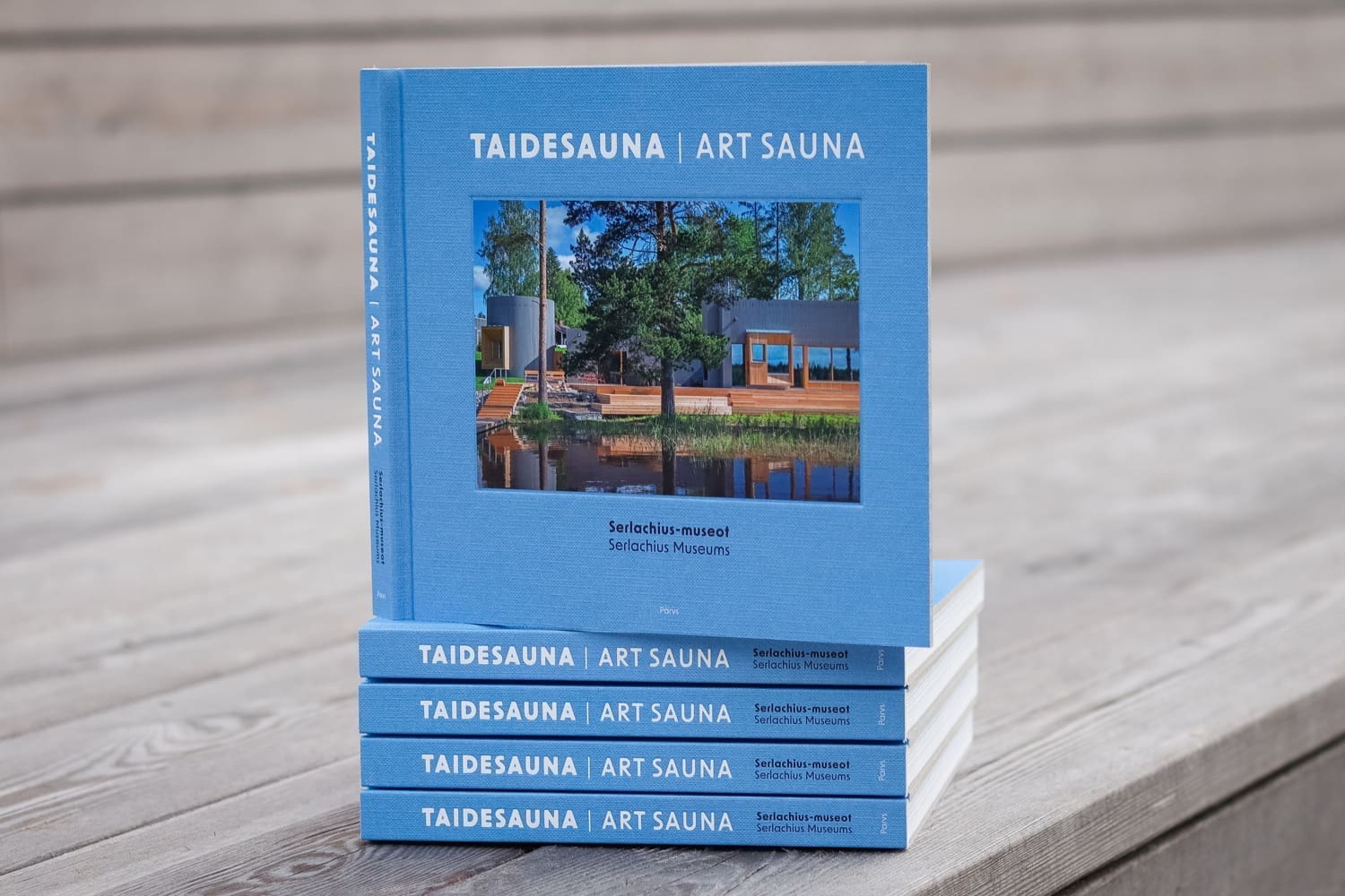Pino sinisiä kirjoja puisella terassilla.