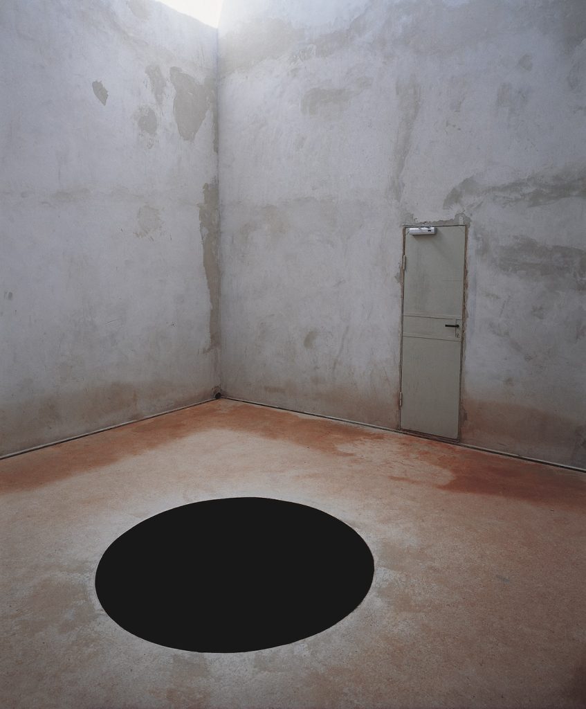 Näyttelytilassa valoa itseensä imevä pyöreä musta aukko.