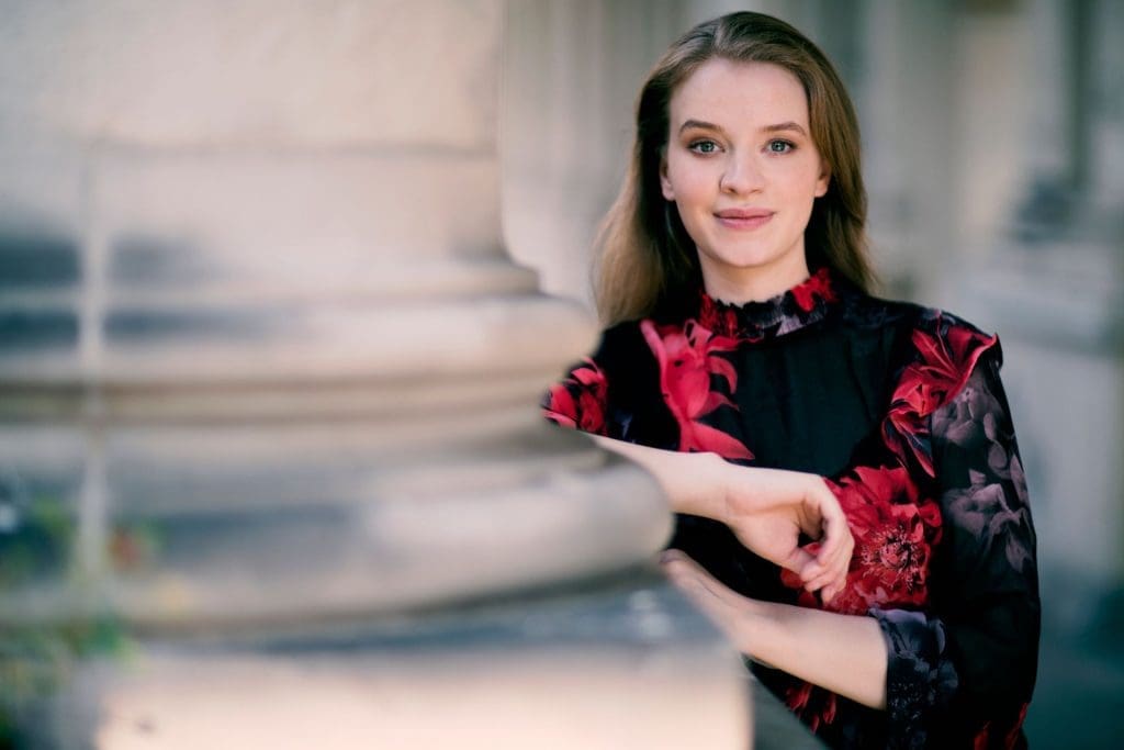 Pianisti Elisabeth Brauss nojaa pylvääseen pieni hymy kasvoillaan.