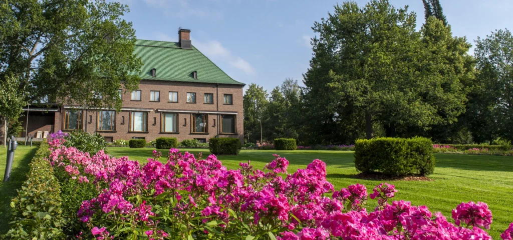 Kesäinen puisto ja kartaorakenus, etualalla pinkkejä kukkia