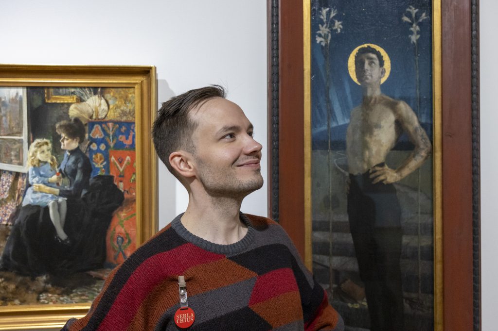 Nuori mies katsoo yläviistoon Gallen-Kallelan taulujen edessä.