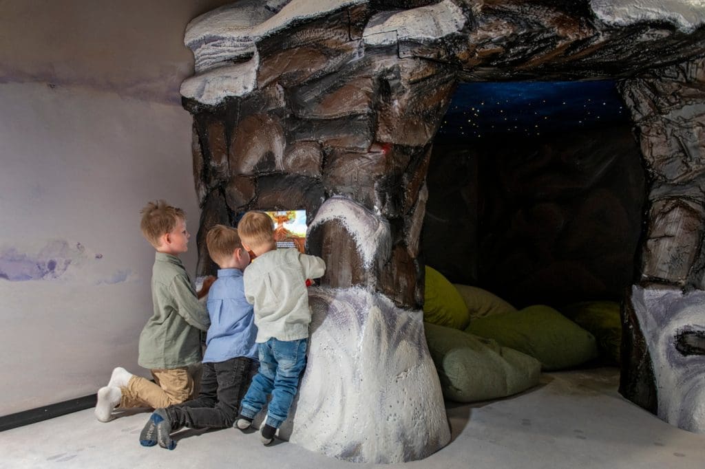 Pienet pojat tutkivat näyttöä lapsille tarkoitetussa metsää kuvaavassa tilassa.
