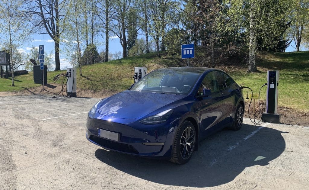 Sininen sähköautoauto latauspaikalla.