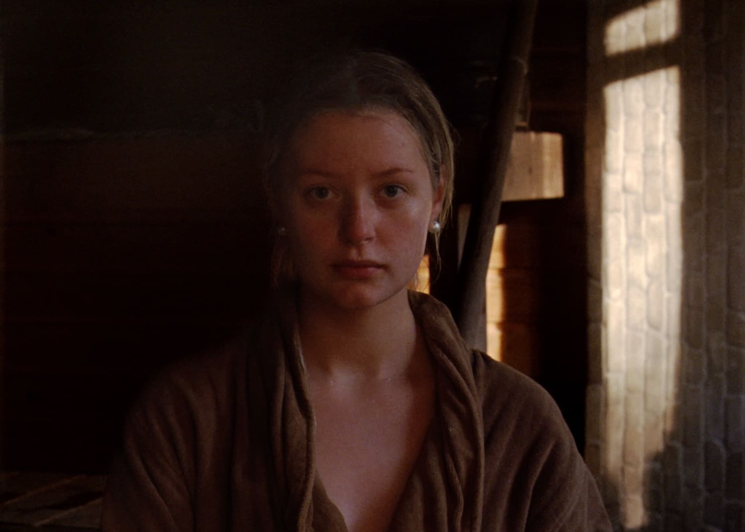 Youn woman is watching to the camera in a dark place.