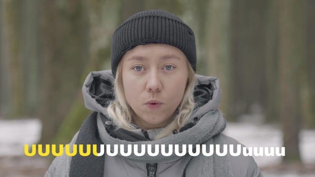 Talvivaatteisiin pukeutunut nuori nainen suipistaa huuliaan lähikuvassa. Alareunassa on ujelluksesta kertova teksti uuuuuuu.