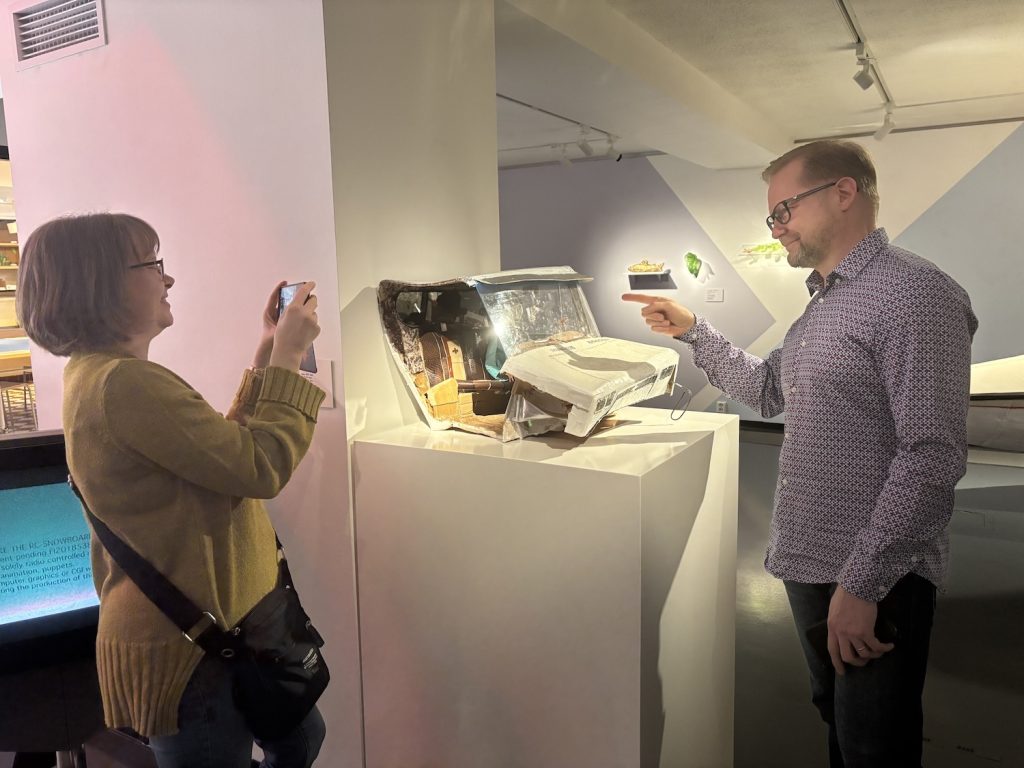 Nainen kuvaa miestä, joka osoittaa taideteosta