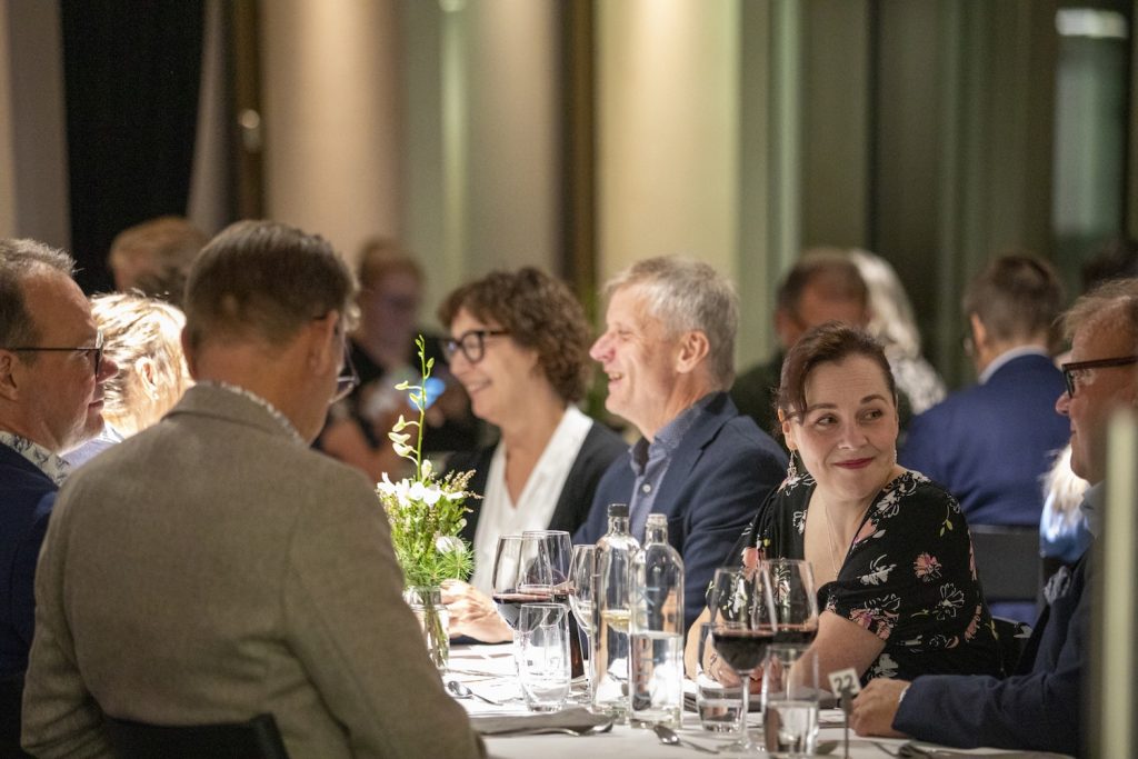 Hyväntuulisia ihmisiä täydessä ravintolasalissa.