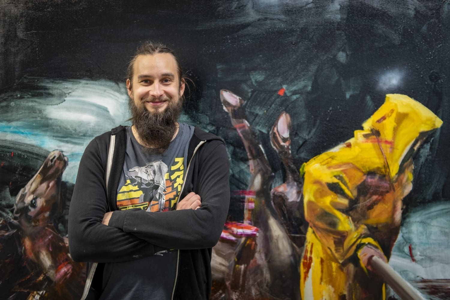 Viljami Heinonen seisoo kädet puuskassa teoskuvansa edessä.